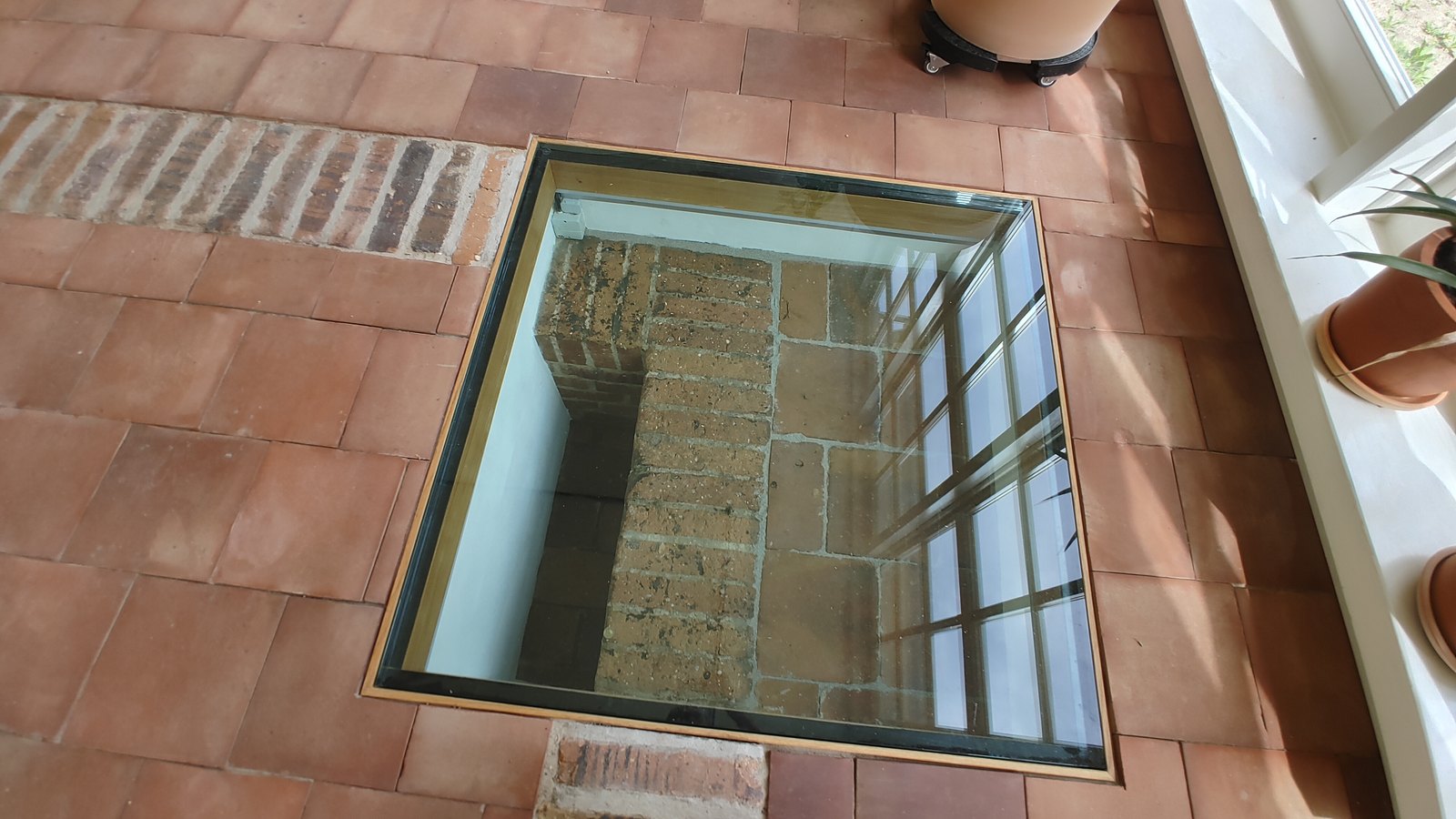 Ein quadratisches, begehbares Glasfeld im Fliesenboden gibt den Blick auf das darunterliegende Mauerwerk frei