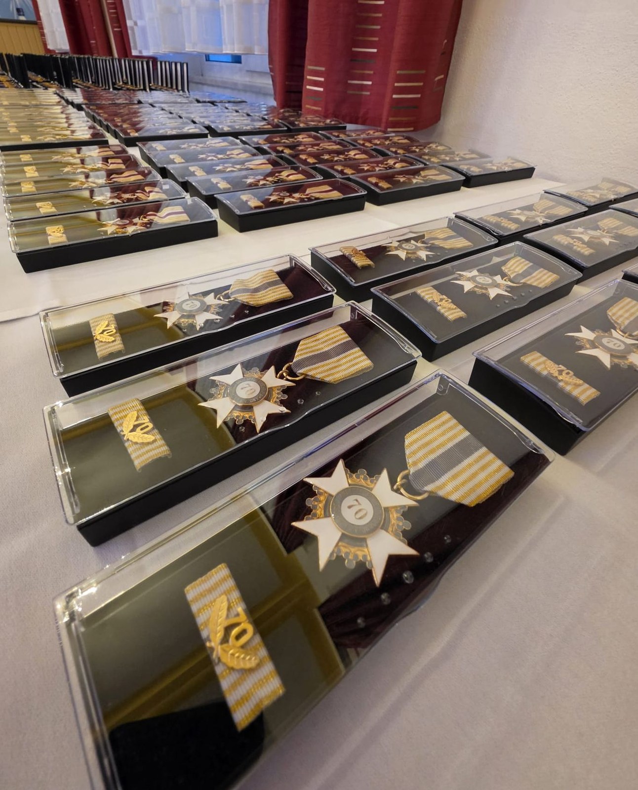 Reihen aufgeklappter Etuis mit goldenen und silbernen Ehrenzeichen auf einem Tisch