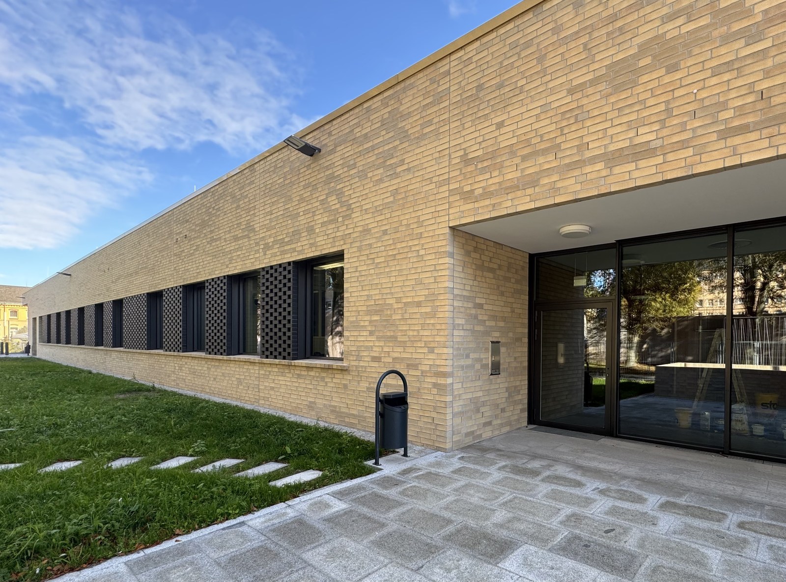 Langgestreckter Neubau mit beigefarbener Klinkerfassade und schmalen Fensterbändern